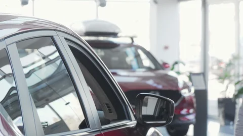 Handsome man smiling to the camera while examining car for sale at dealership Stock Footage 129071969