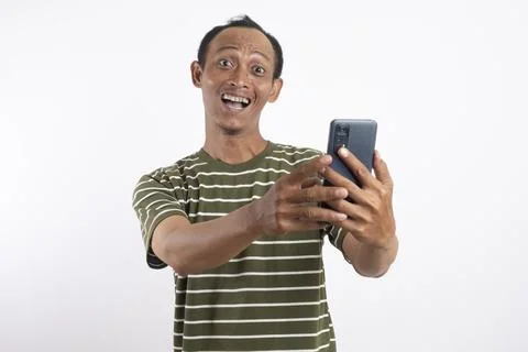 A handsome man smiling while holding a smartphone in a studio setting with .. Фото