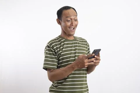 A handsome man smiling while holding a smartphone in a studio setting with .. Stock Photos