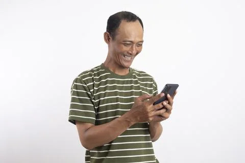 A handsome man smiling while holding a smartphone in a studio setting with .. Fotos de archivo