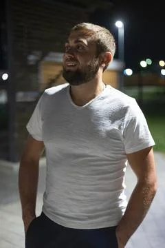 Handsome man smiling while standing in a city park at night in summer. A man Stock Photos