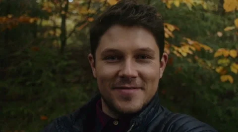 Handsome man spinning around while taking selfie in park. Видео 56876279