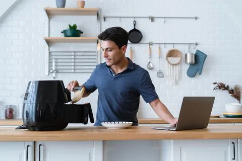 Handsome man standing at kitchen table and cooking toast bread by Air Fryer Stock Photos