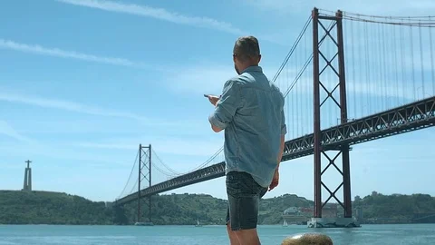 Handsome man standing next to the bridge and chatting on loudspeaker, steadycam Stock Footage