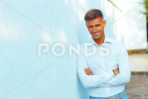 Handsome man standing outdoors with arms folded Stock Photos