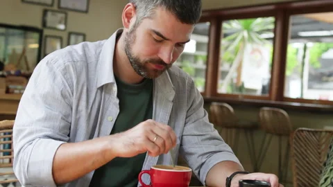 Handsome man stirring coffee in red cup. Stock Footage 272580664