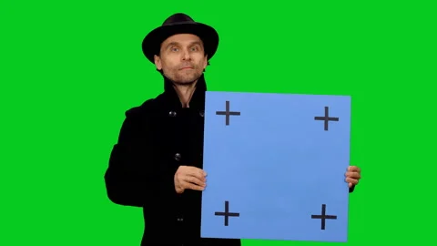 Handsome man in stylish hat walking towards the camera with blue blank board Video stock 130796094