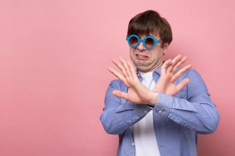 Handsome man in summer glasses making stop sign asking to stay aay from him Stock Photos