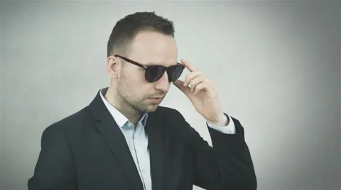 Handsome man in sunglasses smiling on grey background Stock Footage 39735552