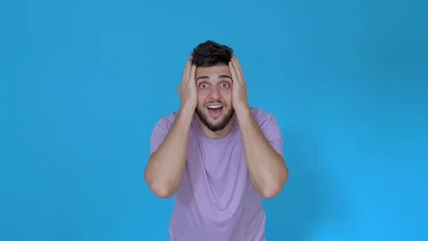 Handsome man surprised curious and happy on blue background wearing t shirt Stock Footage 123944756