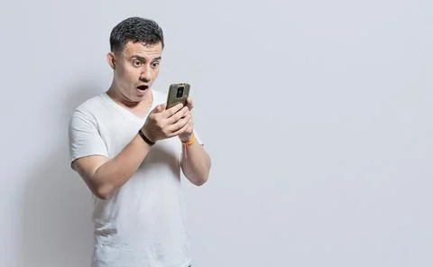 Handsome man with surprised expression with his phone in his hand, An aston.. Stock Photos
