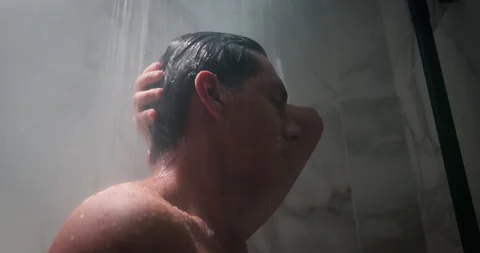 Handsome man take shower standing under hot water stream and relax. Male hygiene 스톡 동영상 338019011
