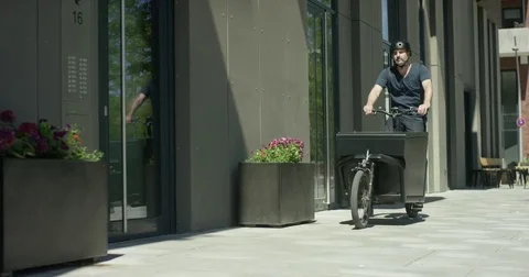 Handsome man takes out a case of his cargo bike and rings a door bell Stock Footage 77547417