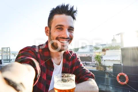 Handsome man taking a selfie drinking a beer at the bar Stock Photos