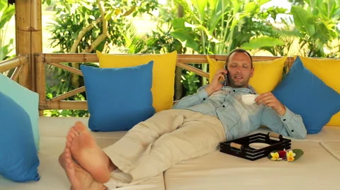Handsome man talking on cellphone and relaxing on gazebo bed in garden HD 스톡 동영상 40759744