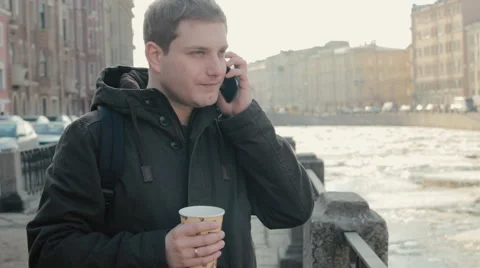 Handsome man talking on a mobile cell phone and enjoying a coffee Stock-Footage 61864485