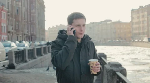 Handsome man talking on a mobile cell phone and enjoying a coffee on the street Video stock 61874991