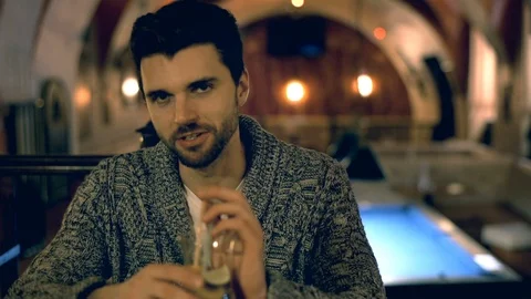Handsome man talking with someone and drinking alcoholic beverage 스톡 동영상 70126453