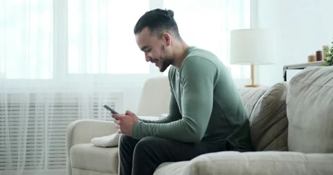 Handsome man text messaging using mobile phone on sofa Stock Footage 156520984