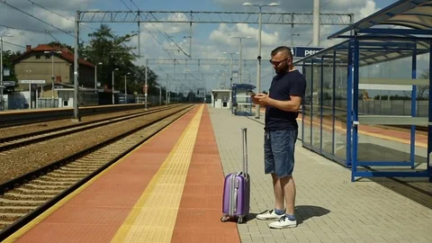 Handsome man texting on smartphone and waiting for the train Stock Footage 78656079