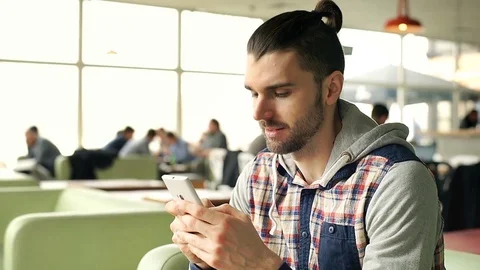 Handsome man texting on smartphone in the cafe and smiling to the camera, steady Stock-Footage 73950699