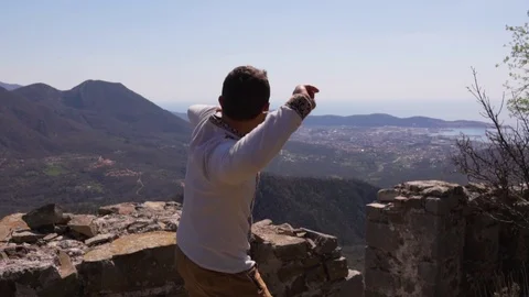 Handsome man is throwing stone in to the cliff. Summer Stock Footage 124715941