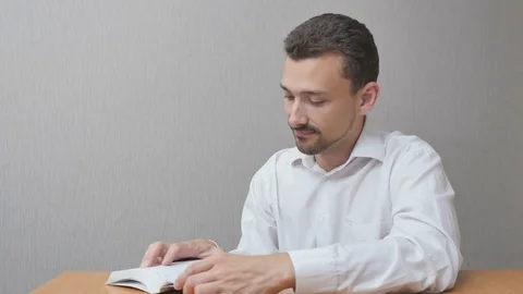 Handsome Man thumbs a book Stock Footage 77080505