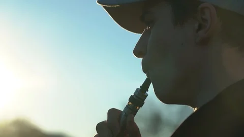 Handsome man in town with an e-cigarette makes a puff Stock Footage 99872072