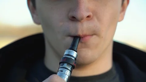 Handsome man in town with an e-cigarette makes a puff Stock Footage 99872386