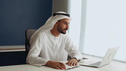Handsome man with traditional clothes working in an office of Dubai Stock Footage 167856724