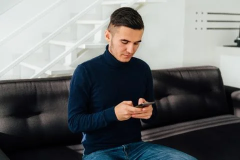 Handsome man typing a message on smartphone, at home Stock Photos