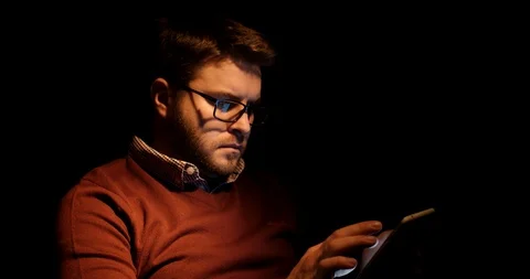 A handsome man uses a tablet in a dark room Stock Footage 88058747