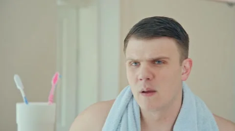 Handsome man using after shave making a face Stock Footage 63920341