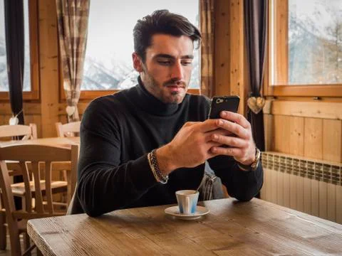 Handsome man using cellphone in cozy ski resort Stock Photos