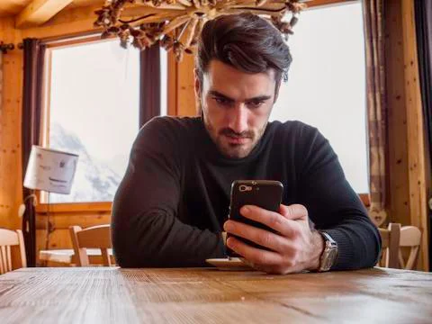 Handsome man using cellphone in cozy ski resort Stock Photos