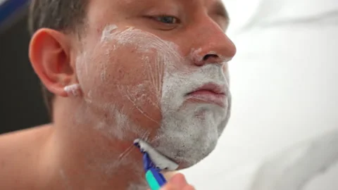 Handsome man using disposable razor for shaving beard and moustache in bathroom Stock Footage 219543551