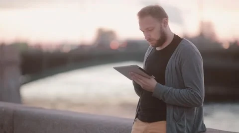 Handsome man using his gadget. Man using a tablet standing on a quay. Cars at Video stock 67949688
