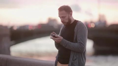 Handsome man using his gadget. Man using a smartphone standing on a quay. Cars Stock Footage 67949893