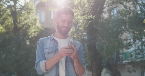 Handsome Man Using his Smartphone while standing outdoor, Smiling and looking Video stock 122994895