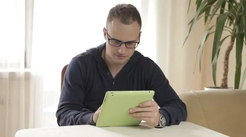 Handsome man using his tablet pc relaxing on chair Stock Footage 43219404