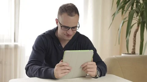 Handsome man using his tablet pc relaxing on chair Video stock 43219408
