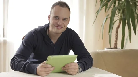 Handsome man using his tablet pc relaxing on chair Stock Footage 43219418