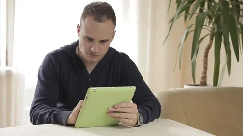 Handsome man using his tablet pc relaxing on chair Video stock 43219423