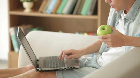 Handsome man using laptop and eating apple Video stock 27692077
