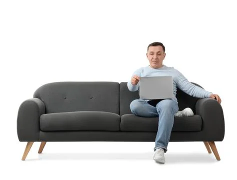 Handsome man using laptop on sofa against white background Stock Photos