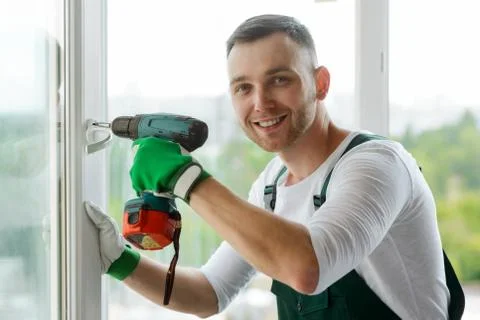 Handsome man using a screwdriver to install a window handle Stock Photos