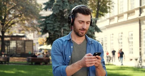 Handsome Man using Smartphone and Headphone receiving Good Massage and became Stock Footage 99235293