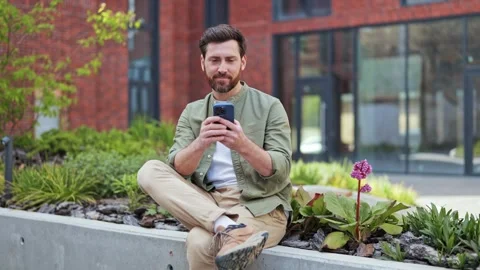 Handsome Man Using Smartphone, Browsing Social Media, Smiling Outdoors Stock Footage 309079896