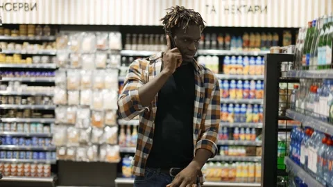 Handsome man using smartphone, pushes shopping cart, walks at the store Stock Footage 151321239