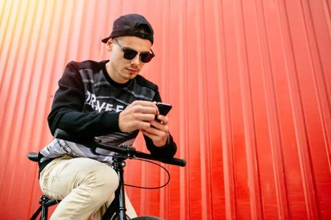 Handsome man using a smartphone while sitting on the bike Stock Photos